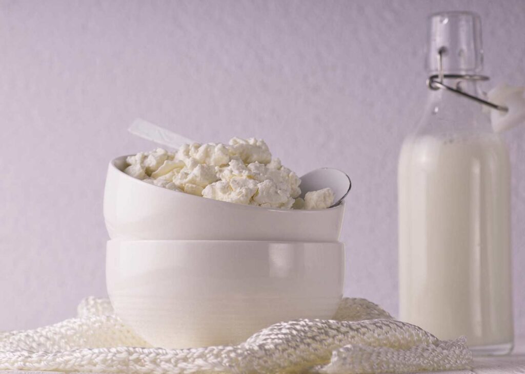 A picture of fresh cottage cheese next to a bottle of milk